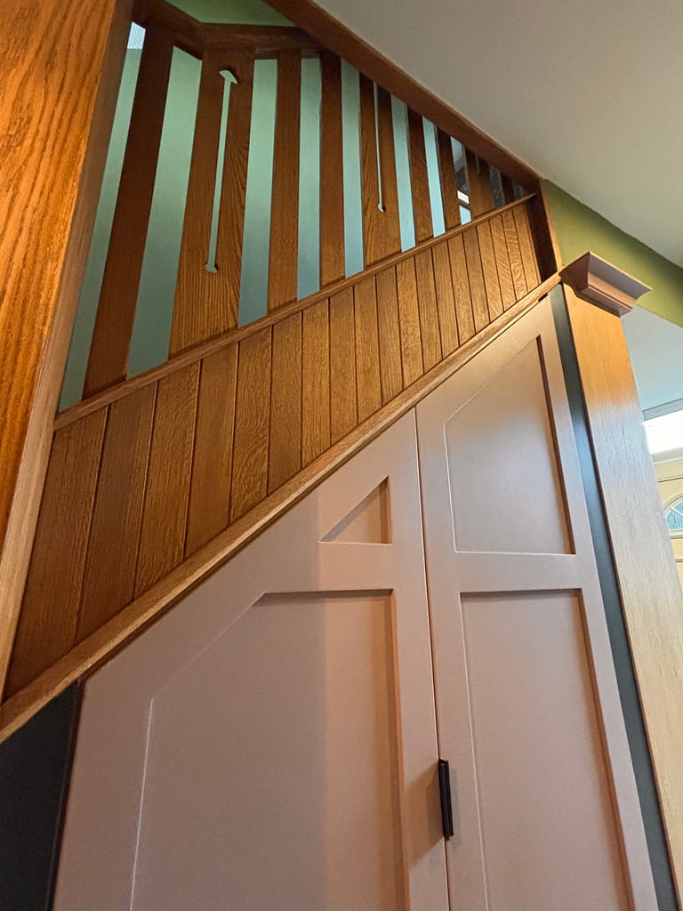 Bespoke staircase showing custom under stair doors and spindles above